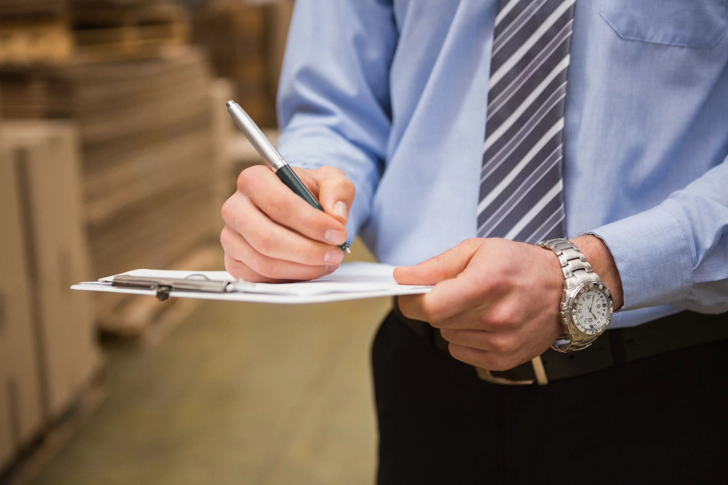36347863 - warehouse worker checking his list on clipboard in a large warehouse Business professional writing on a clipboard